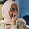 amina on the bus, covering her laugh with her hand